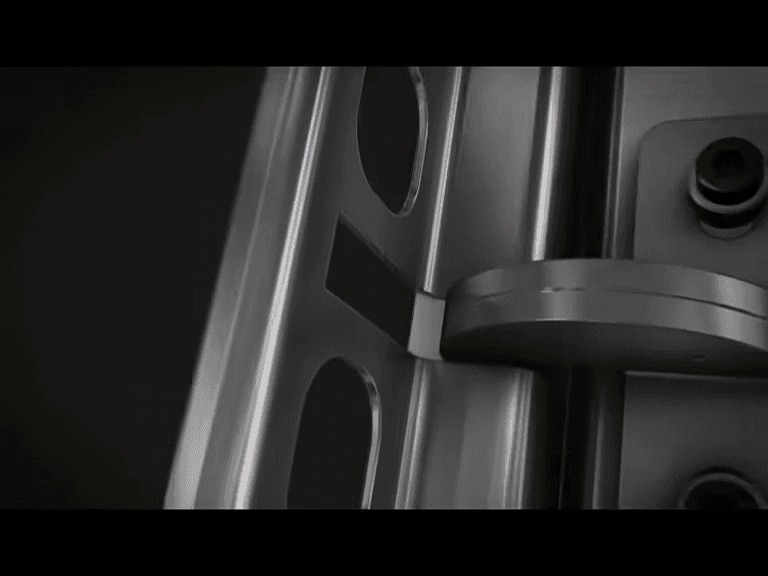 A curved METAGRIP metal link inside the vertical profiles, beside elongated openings and dark mounting fasteners.