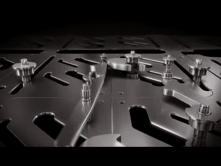 The REFLEX mechanism’s slotted steel plate, shaped cutouts, headed pins and mechanical linkage.